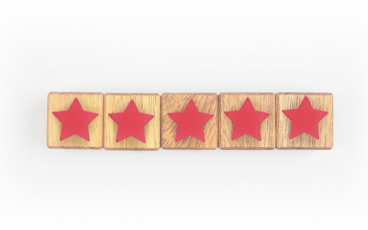 Five wooden blocks in a row, each painted with a red star