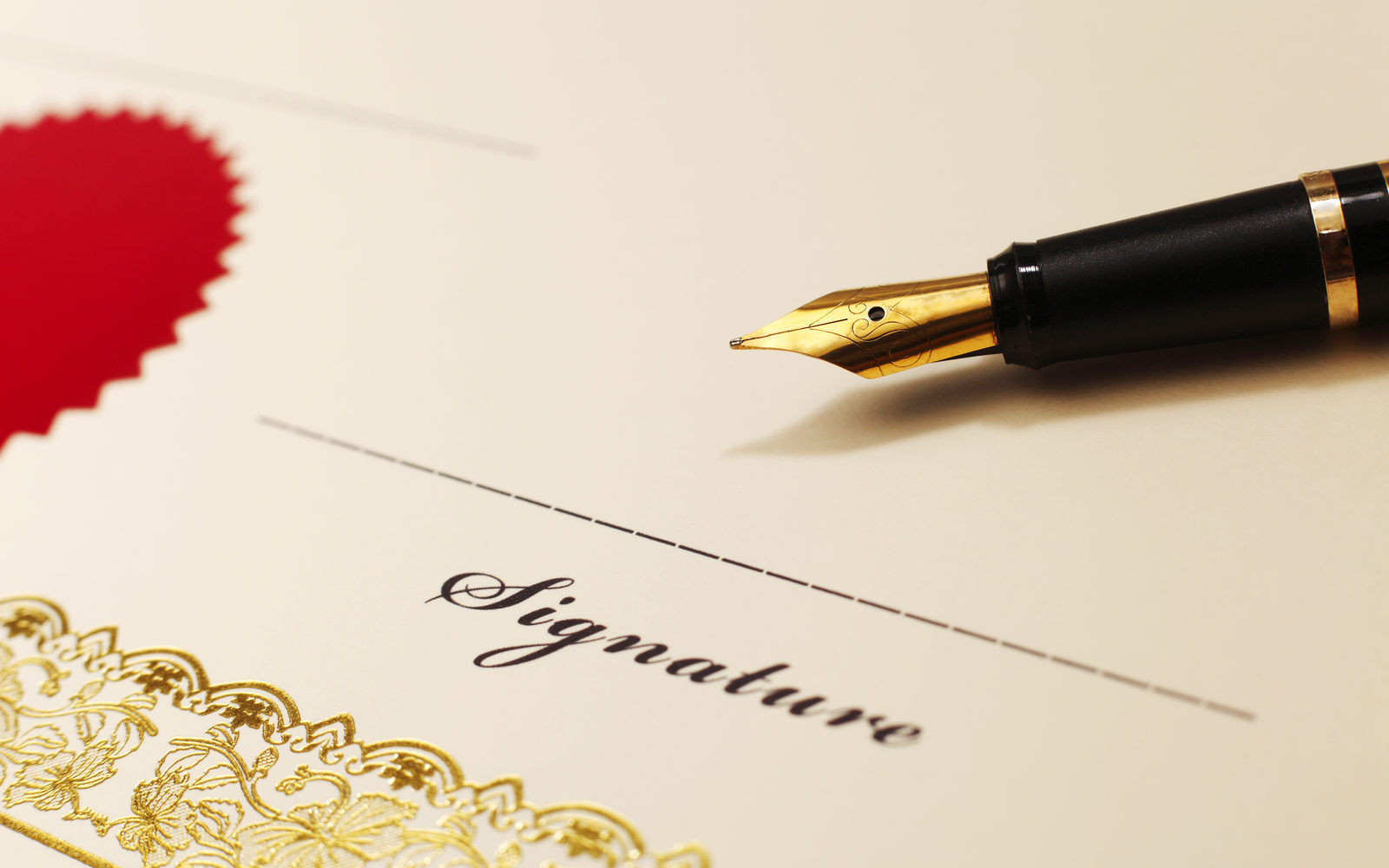 Certificate with a red seal, gold border and a fountain pen by the signature line