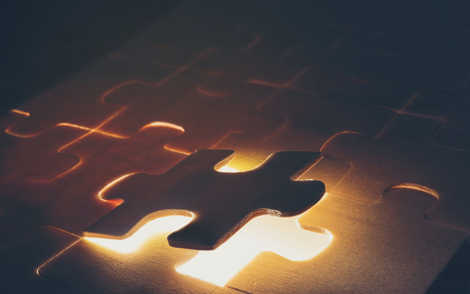 A puzzle piece about to drop into its glowing slot, lit warm amber from below