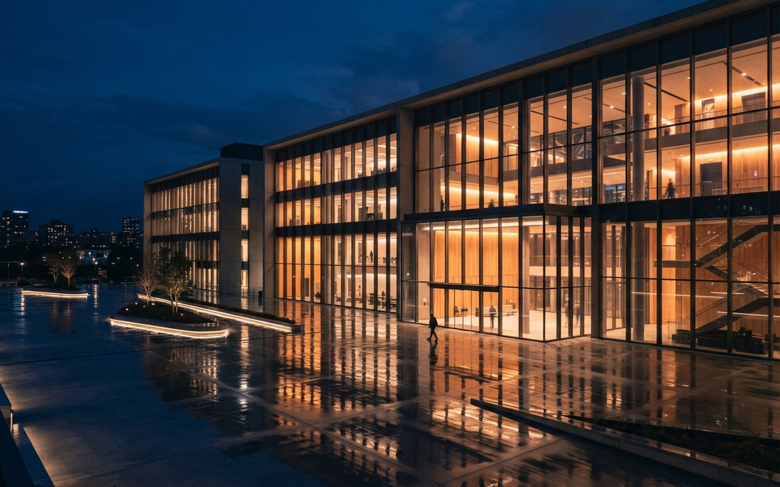 A large glass-walled technology company headquarters glowing warm at dusk