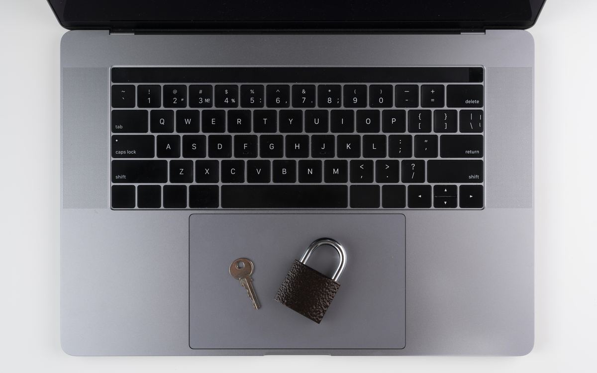 Padlock and small key resting on a silver laptop trackpad, top view