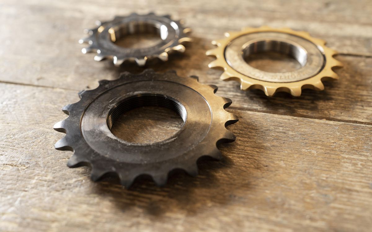Three metal gears resting together on a worn wooden table